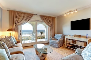 Relax in this stylish living room with a comfortable sofa, armchair, and large windows offering a view of the outdoors.
