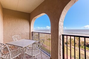 Enjoy the ocean view from this balcony with a table and two chairs.