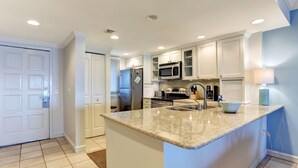 A modern kitchen with white cabinetry, granite countertops, stainless steel appliances, and recessed ceiling lighting. - Beautiful 2br/2ba Oceanfront, Sea Dunes  (Amelia Island)