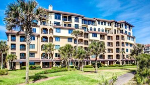 A multi-story hotel with a central courtyard, palm trees, and a well-maintained lawn. - Beautiful 2br/2ba Oceanfront, Sea Dunes  (Amelia Island)