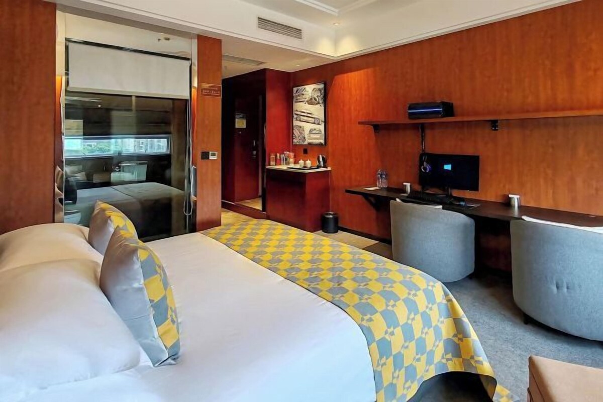 A hotel room with a large bed, a desk, a chair, and a television.