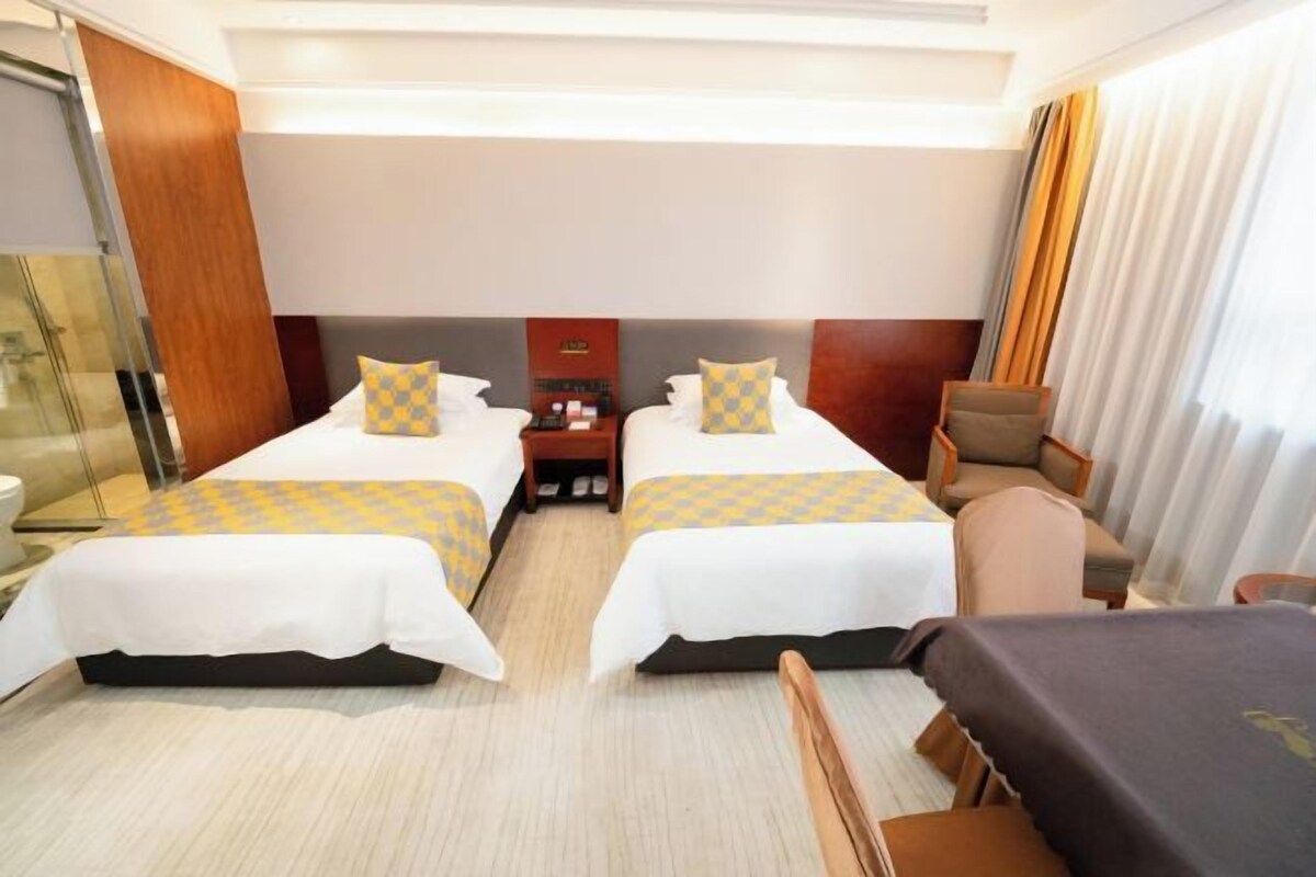 A hotel room with two beds, a desk, a chair, and a small table.
