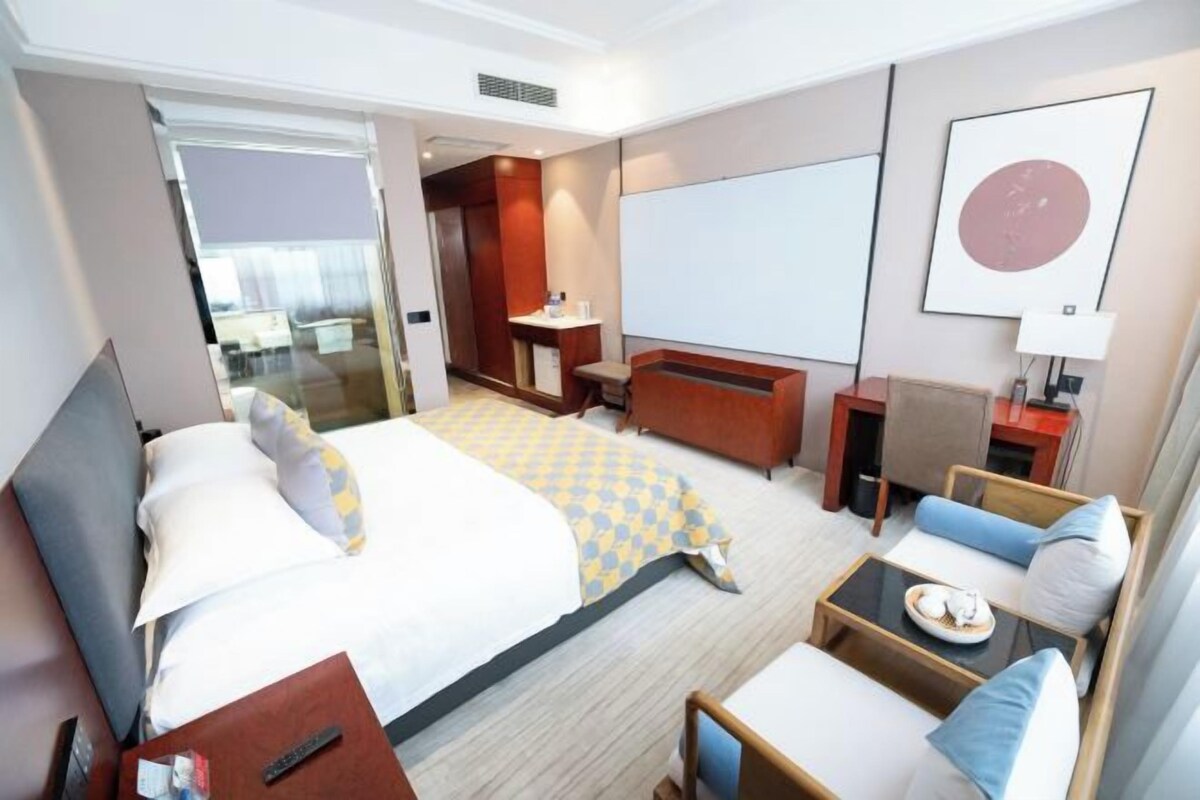 A hotel room with a bed, a sofa, a desk, and a TV.