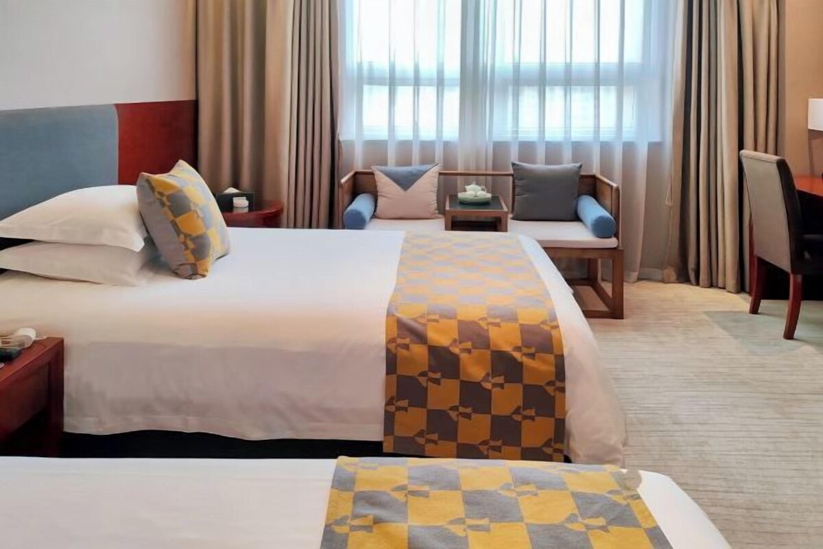 A hotel room with two beds, a desk, and a chair.