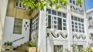 Un edificio con fachada blanca, ventanas amplias y una escalera que conduce a la entrada.