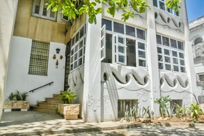 Ein Gebäude mit weißer Fassade, großen Fenstern und einer Treppe, die zum Eingang führt.
