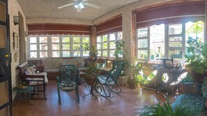 Un interior acogedor con un sofá, sillones mecedores y plantas en macetas.