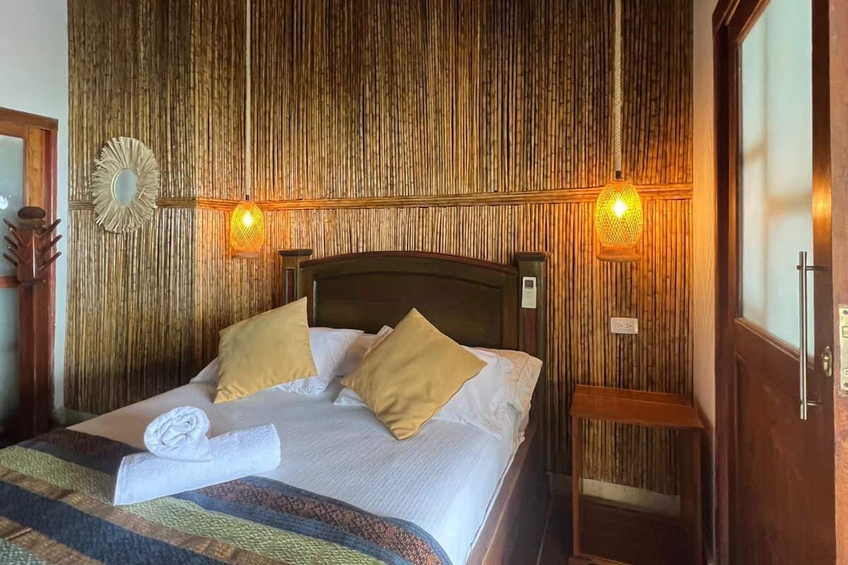 A neatly made bed with a striped blanket, a wooden headboard, and two bedside lamps.