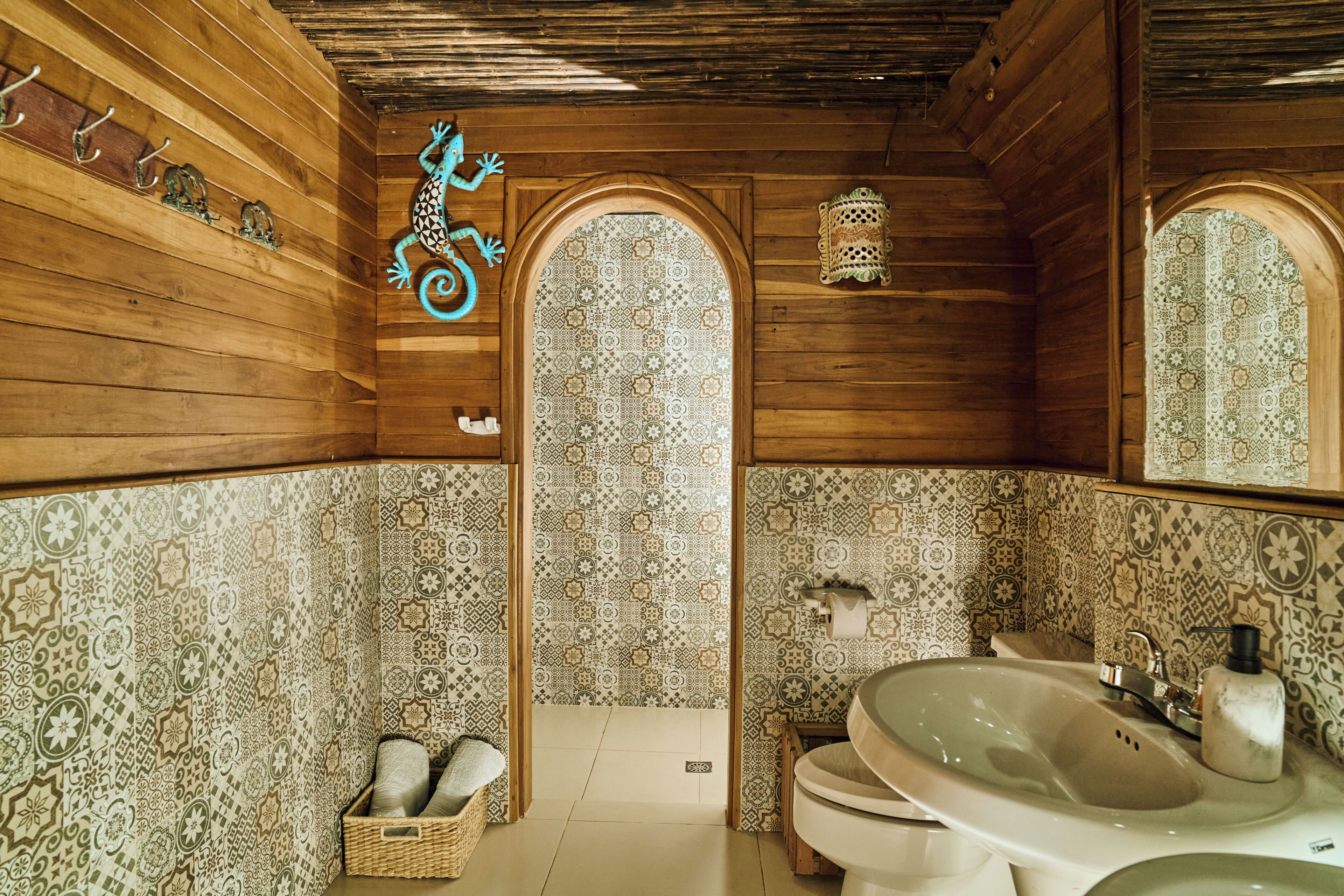 A wooden interior with a tiled wall, a sink, and a mirror.