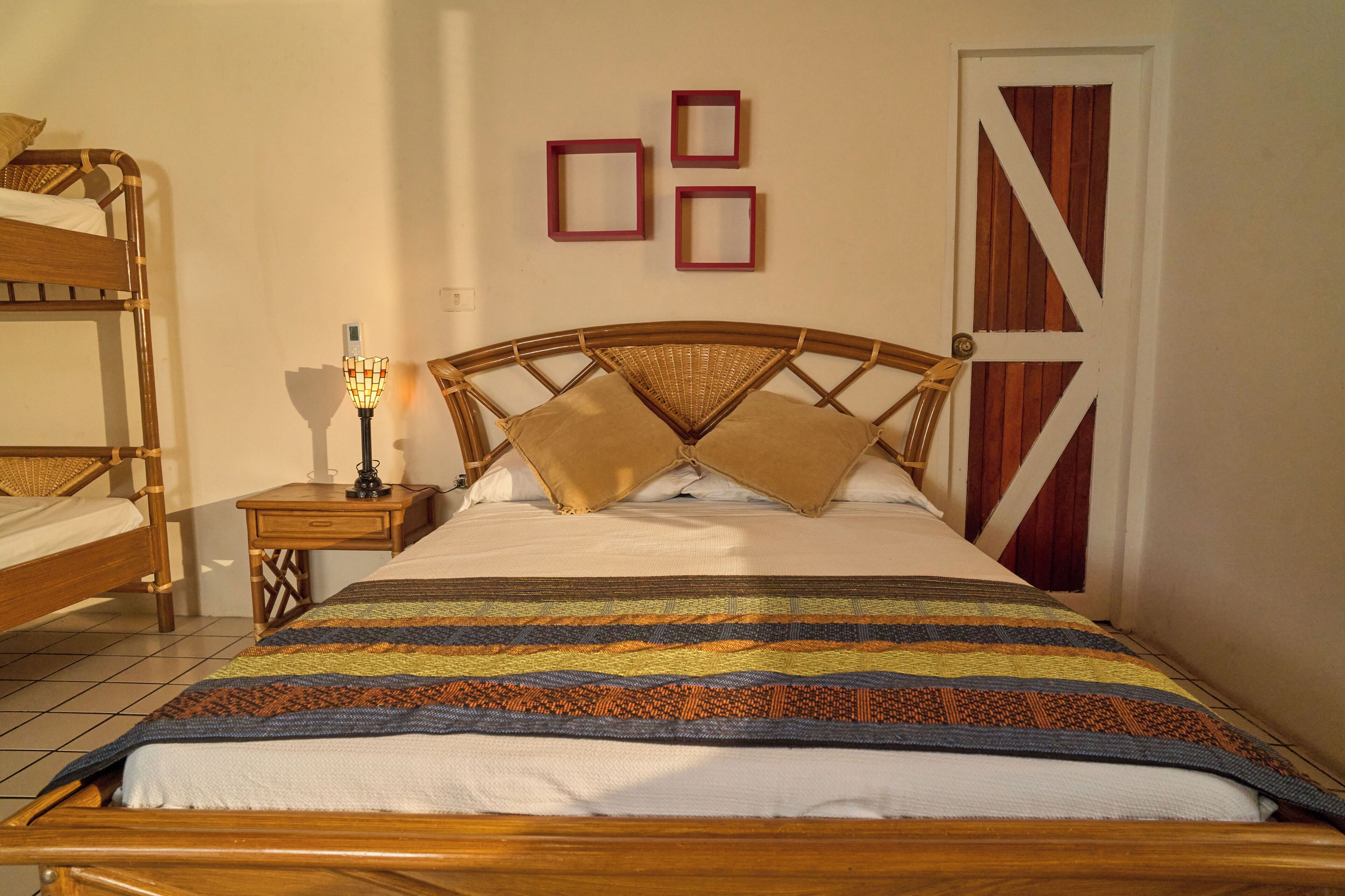 A room with a single bed, a nightstand, a lamp, and a door with a wooden panel.