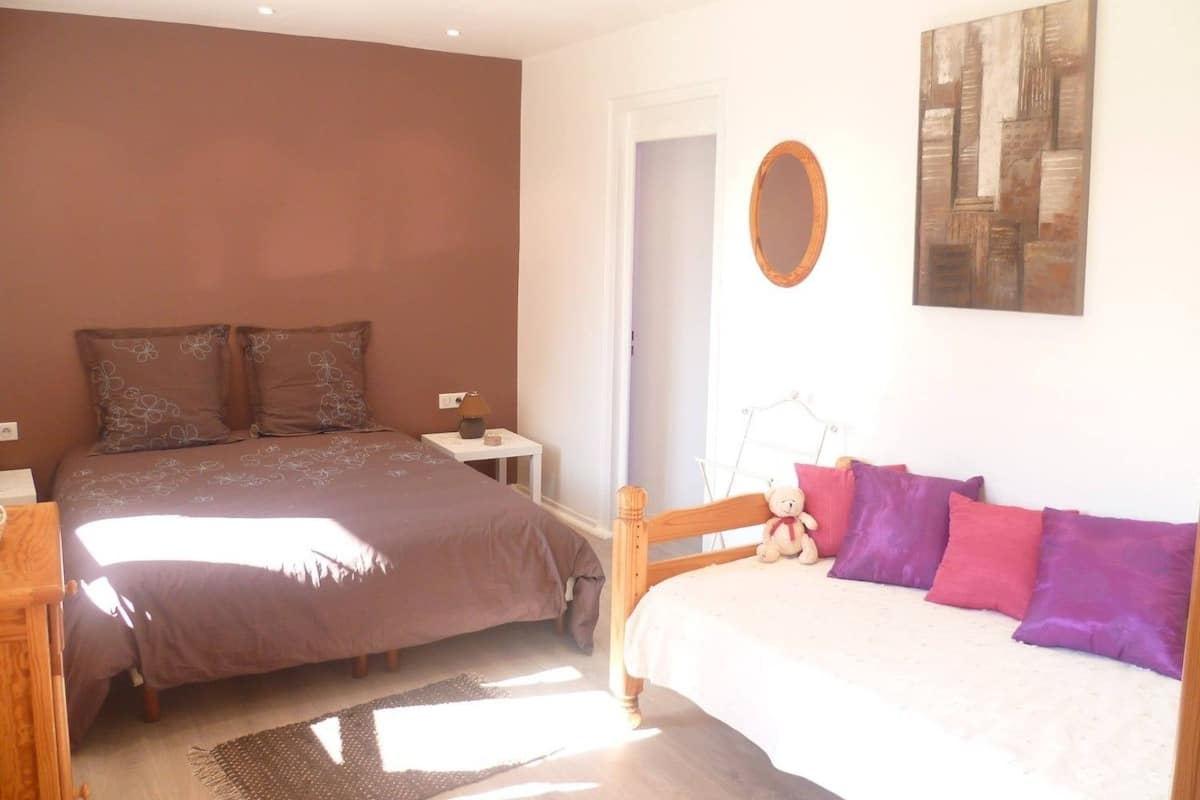 A bedroom with two beds, a nightstand, a lamp, a mirror, and a painting on the wall.