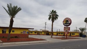 Un motel con fachada amarilla, palmeras y un letrero que indica internet gratuito.
