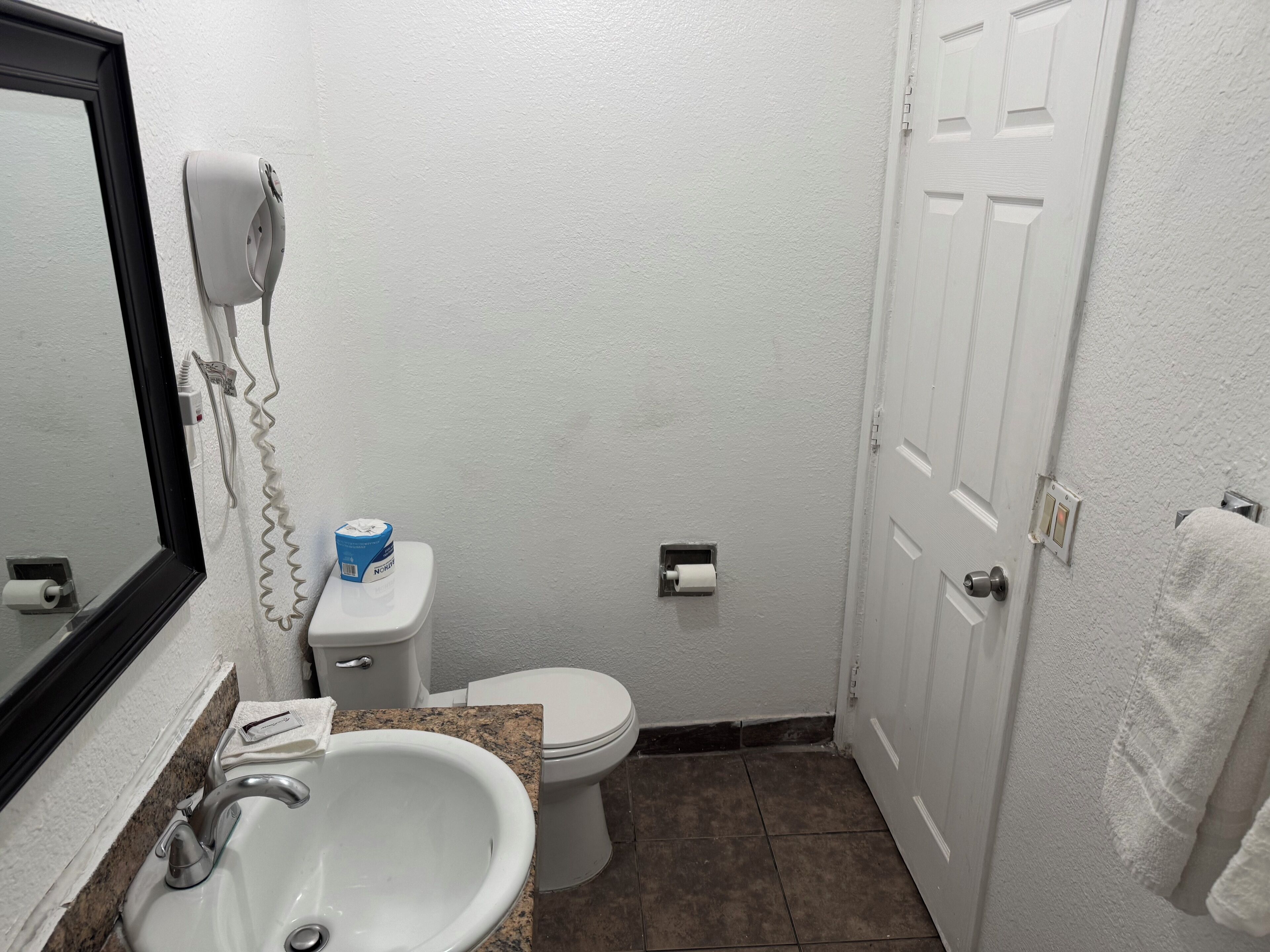 Un baño pequeño con lavamanos, inodoro y un secador de pelo en la pared.