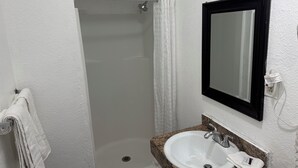 Un baño con lavamanos blanco, espejo y ducha con cortina.