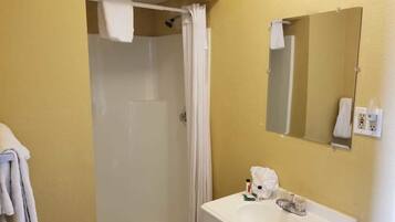 Une salle de bain équipée d’une douche, d’un lavabo, d’un miroir et d’un porte-serviettes.
