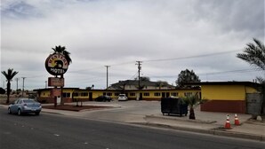 Un motel con un letrero llamativo, un estacionamiento y un edificio de paredes amarillas y rojas.