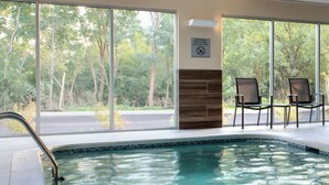 A swimming pool with a view of trees, a no diving warning sign, and two chairs. - Fairfield Inn & Suites by Marriott Buffalo Amherst/University (Buffalo)