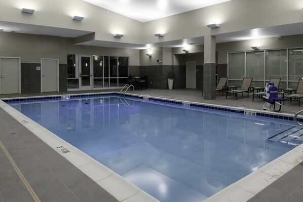 Piscina com faixas demarcadas, área de estar com cadeiras e um balcão de recepção.