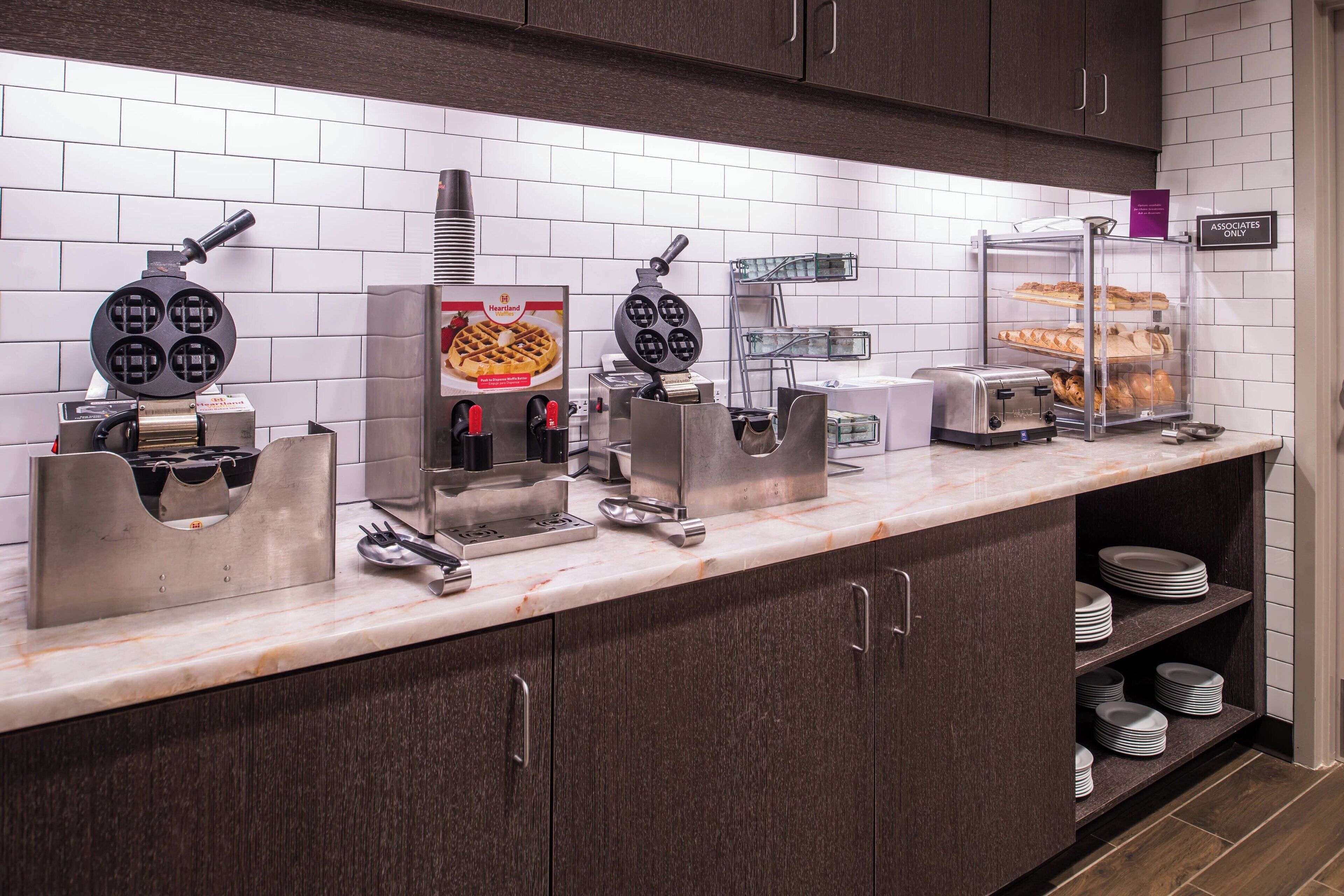 A breakfast bar with waffle makers, a waffle display, and a toaster.