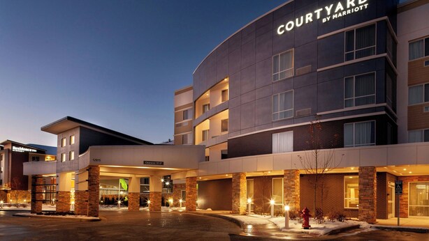 Un hôtel Courtyard by Marriott au design moderne, avec plusieurs étages et une entrée bien éclairée.