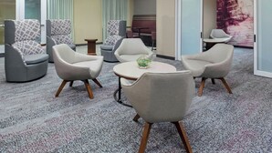 Un espace de détente moderne, composé d’un mélange de fauteuils et de canapés, d’une table ronde agrémentée d’un objet décoratif et d’un coin salon avec un canapé rouge.