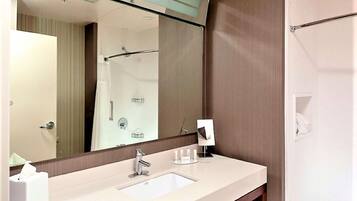 A modern bathroom with a large mirror, a sink, and a shower area.
