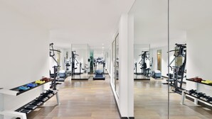 Ein modernes Fitnessstudio mit unterschiedlichen Trainingsgeräten, Spiegelwänden und ordentlich gestapelten Hanteln.