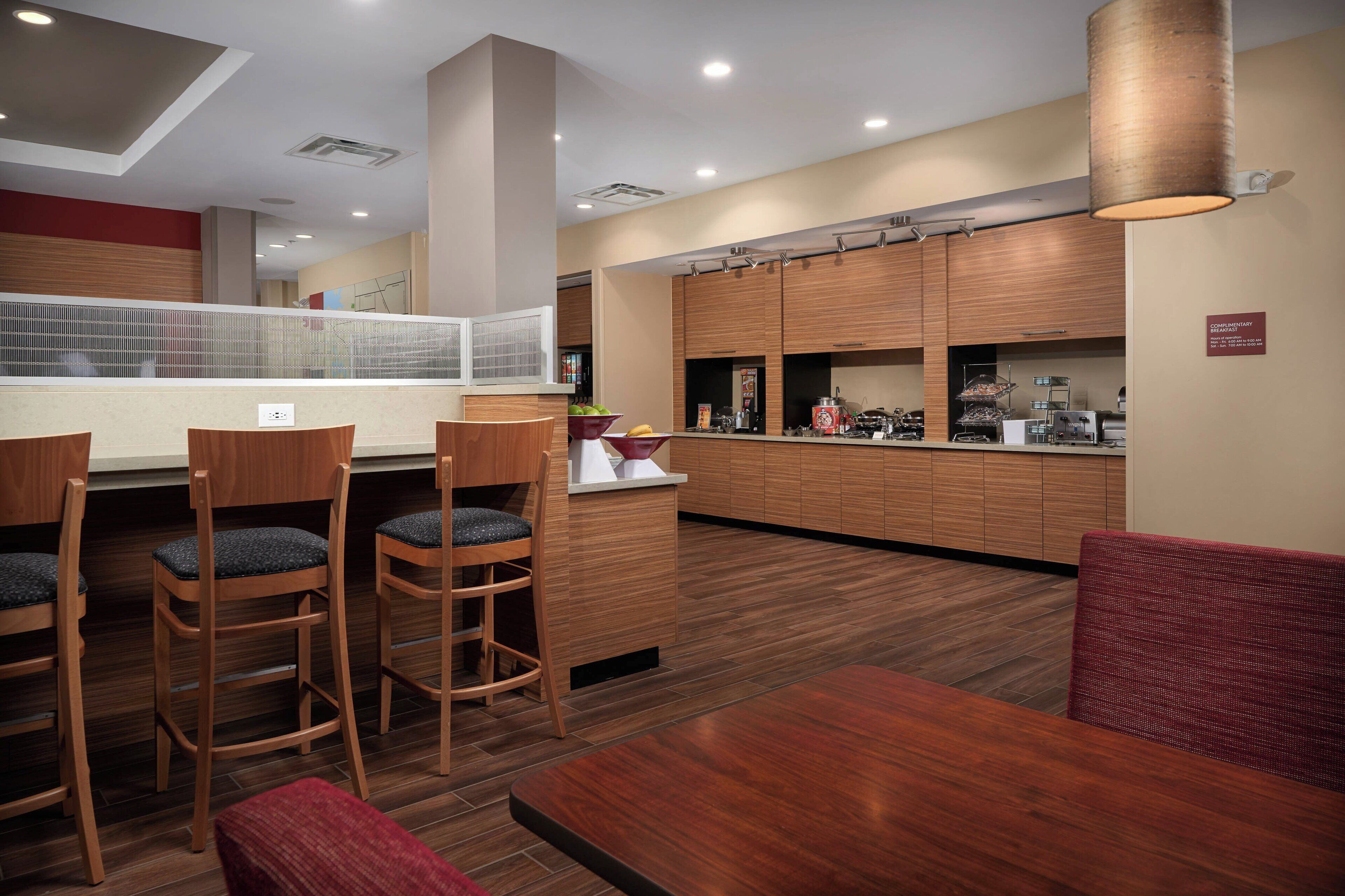 A modern restaurant with wooden furniture, a counter, and a kitchen area.