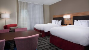 Une chambre d’hôtel avec deux lits, un bureau et une chaise.