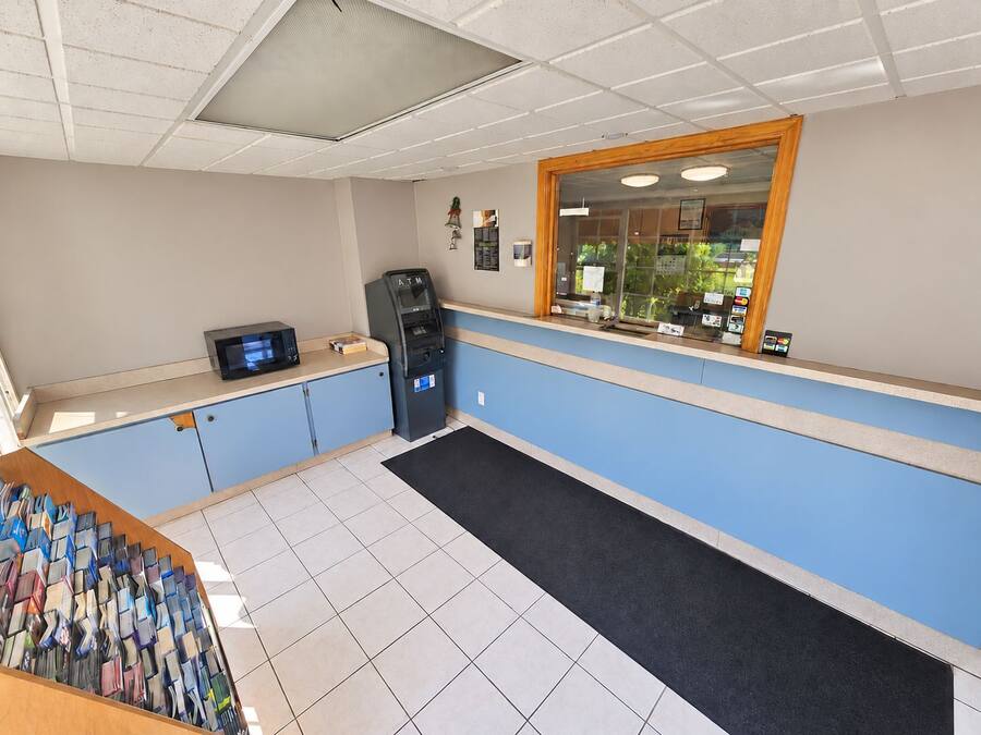 Un espace d’accueil comprenant un comptoir, un distributeur automatique de billets et une fenêtre donnant sur un espace verdoyant.