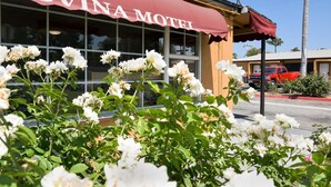 Um motel chamado 'COVINA MOTEL' com toldo vermelho, rodeado por flores brancas.