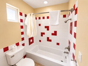 A bathroom with a bathtub, toilet, and a shower area. - Covina Motel (West Covina)