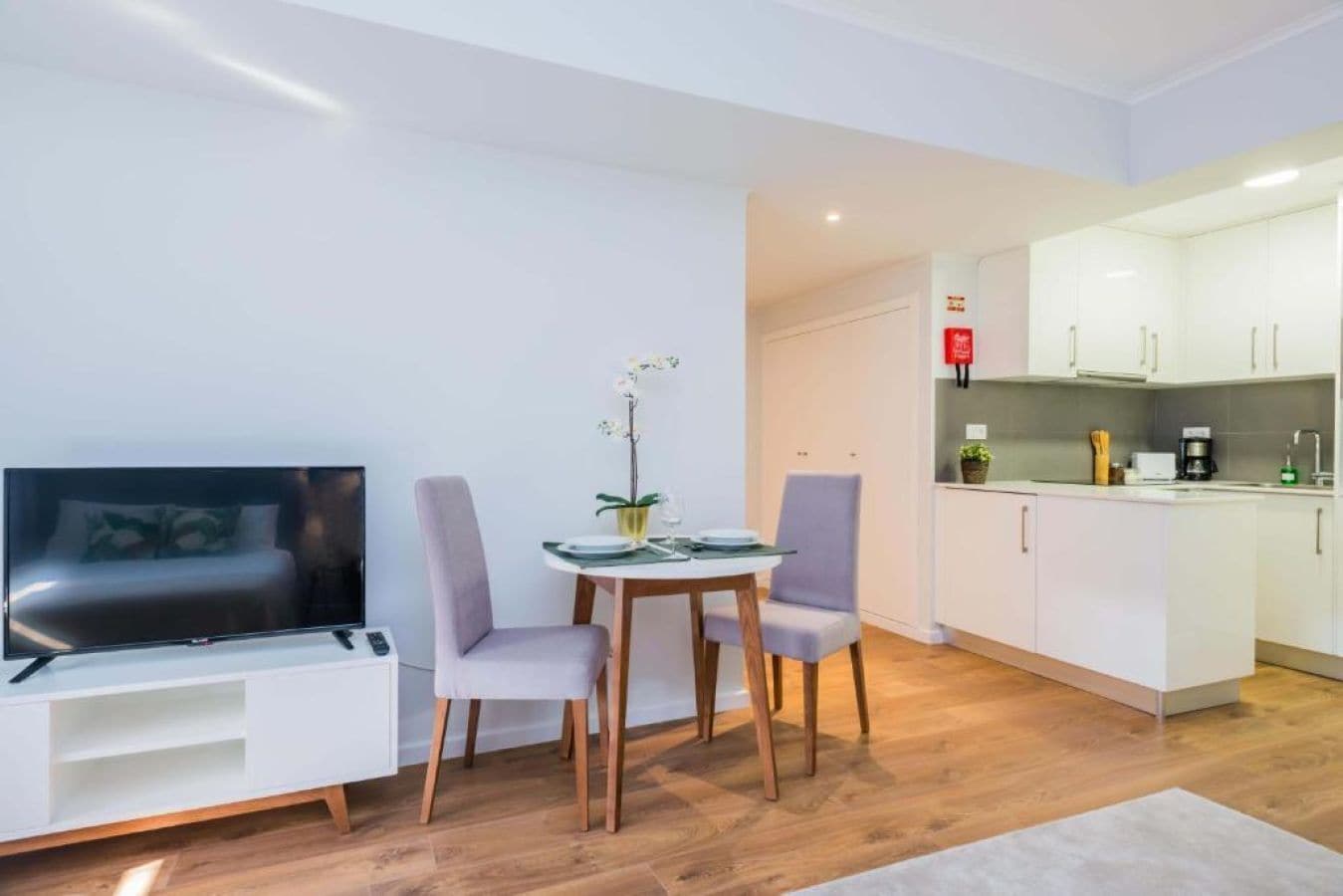 Un espace de vie compact comprenant un téléviseur, un coin salon et une kitchenette.