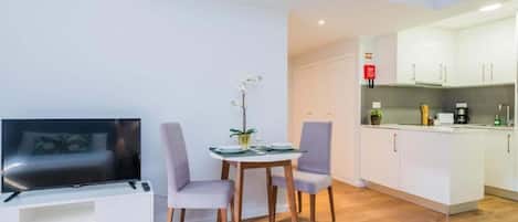 A compact living space with a TV, seating area, and kitchenette.