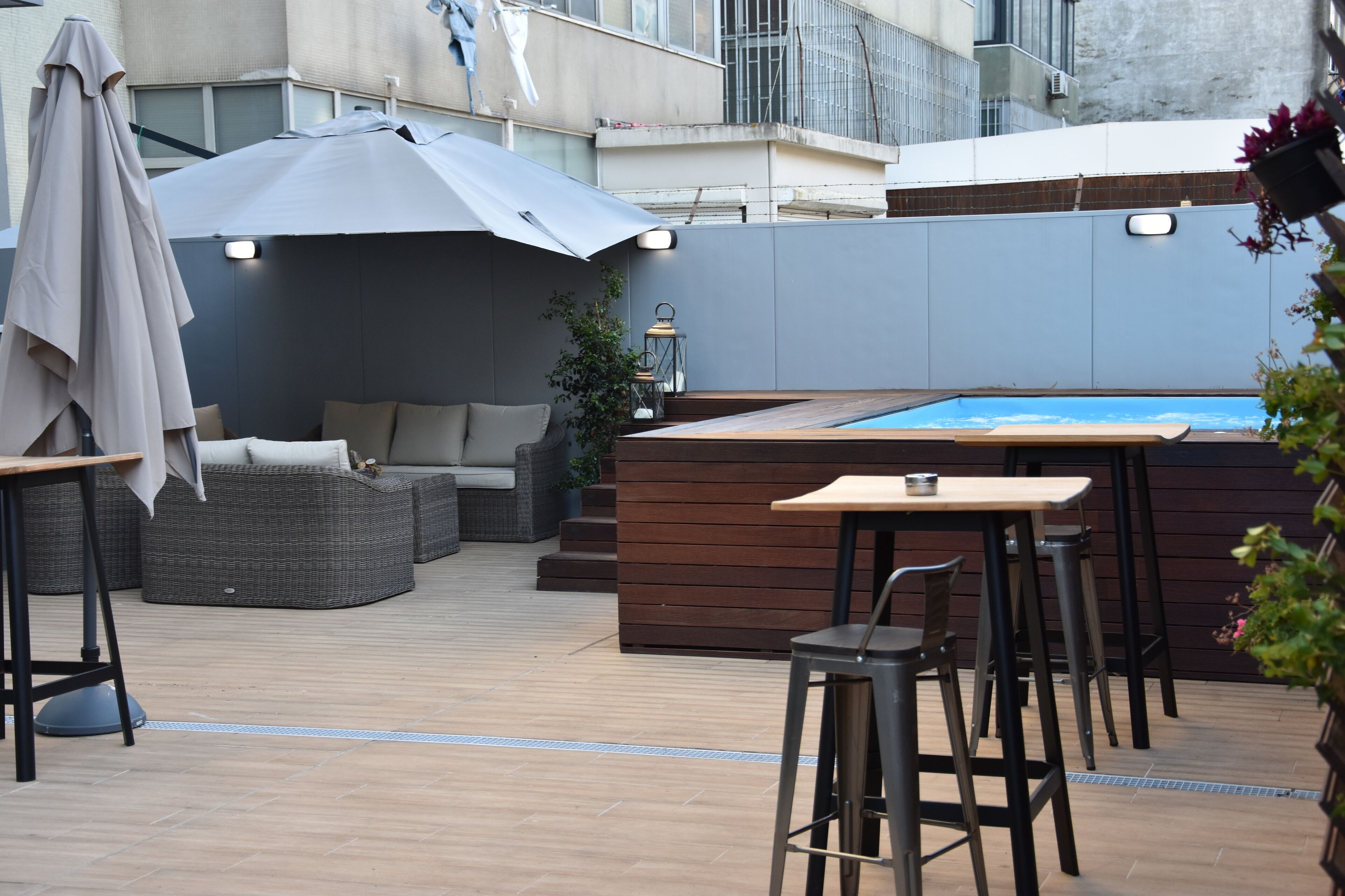 Patio esterno con piscina, sgabelli da bar, un divano e una zona salotto coperta.