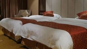 A hotel room with a large bed, a chair, and a mirror on the wall. - Jun Hao Sunshine Hotel (Suining)