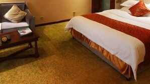 A hotel room with a bed, a nightstand, and a wall-mounted lamp. - Jun Hao Sunshine Hotel (Suining)