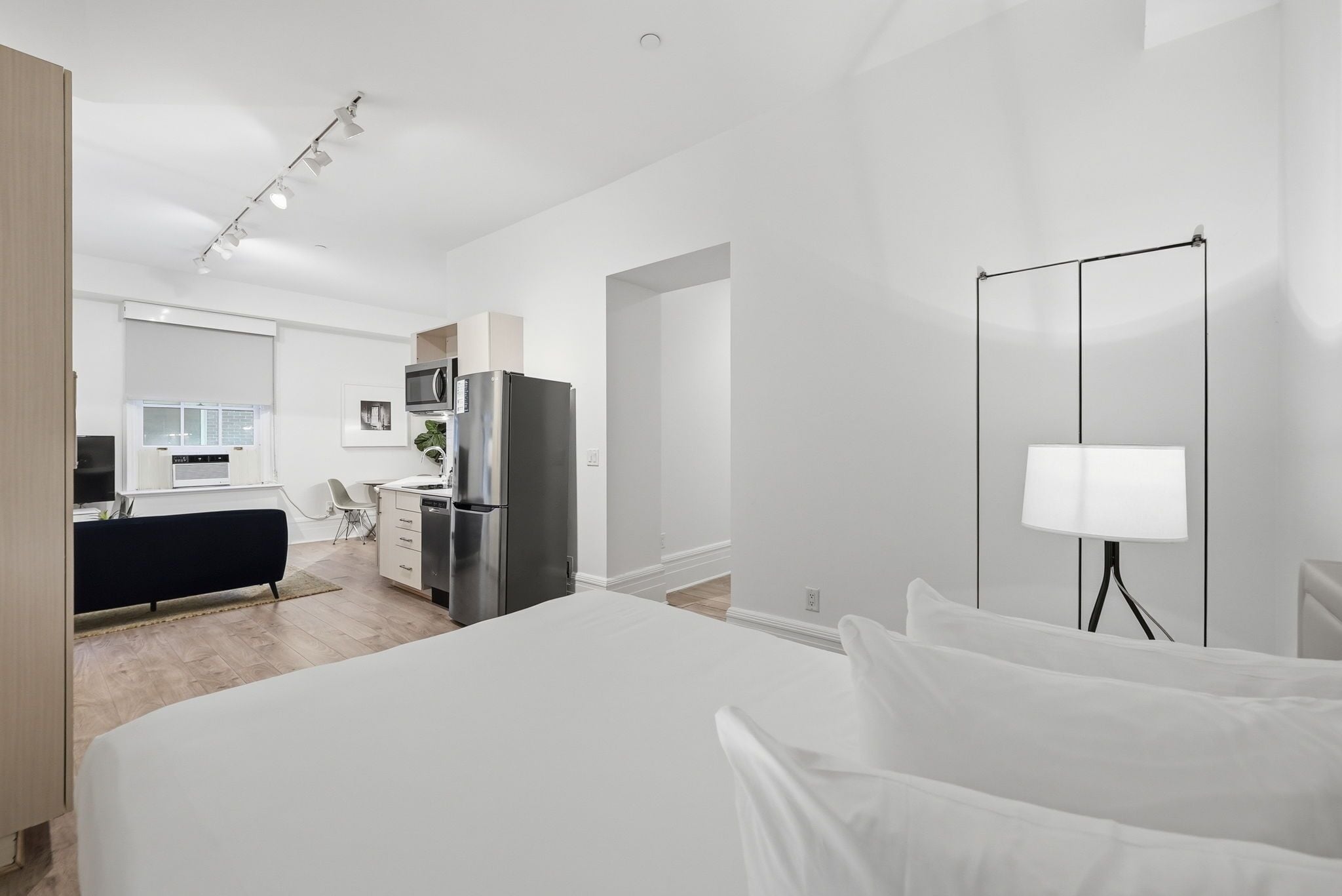 Una habitación de hotel moderna con una cama grande, un escritorio, un refrigerador y un televisor.