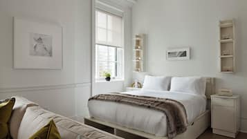 Un dormitorio minimalista con una cama grande, mesitas de noche y estanterías empotradas.