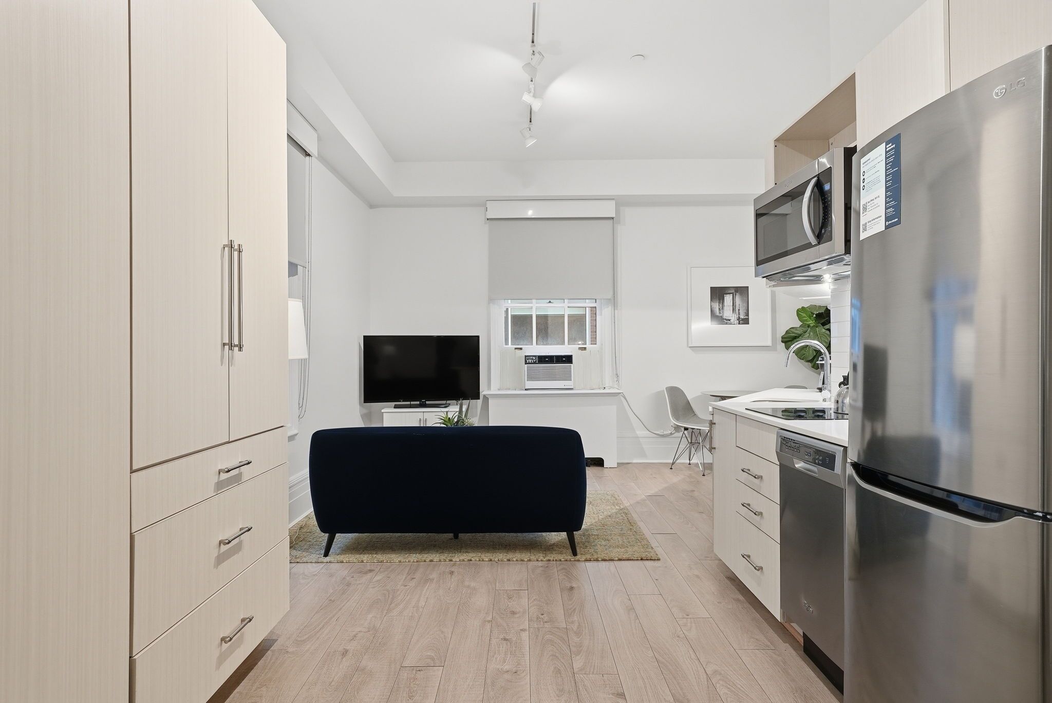 Una cocina moderna con un televisor de pantalla plana, un microondas y un refrigerador.