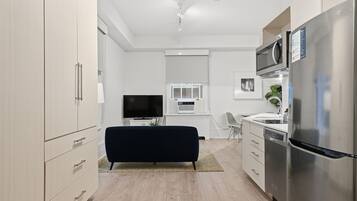 Una cocina moderna con un televisor de pantalla plana, un microondas y un refrigerador.