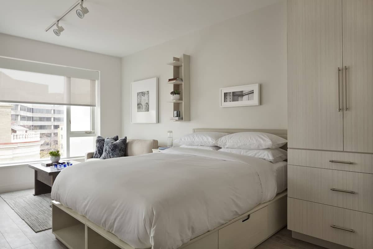 A bedroom with a bed, bedside table, lamp, and wardrobe.