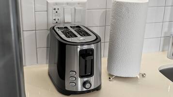 A kitchen with a toaster, a roll of paper towels, and a white tiled backsplash.