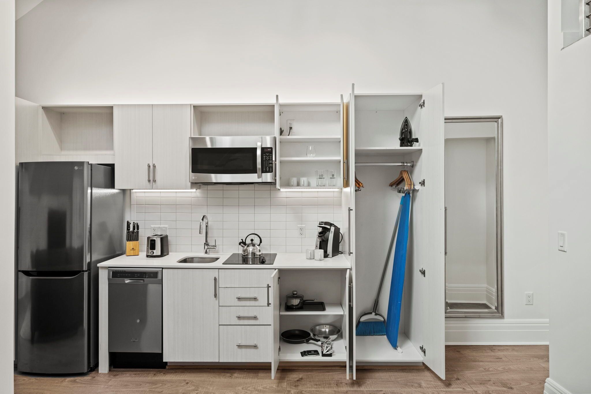 A modern kitchen with white cabinetry, a stainless steel refrigerator, a microwave, and a dishwasher.