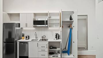 A modern kitchen with white cabinetry, a stainless steel refrigerator, a microwave, and a dishwasher.