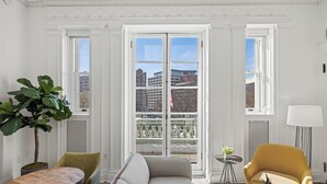 A room with a large window, a sofa, a table, a chair, and a lamp. - Placemakr Dupont Circle (Washington)