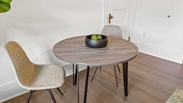 A dining table with a bowl of fruit, two chairs, and a door in the background.