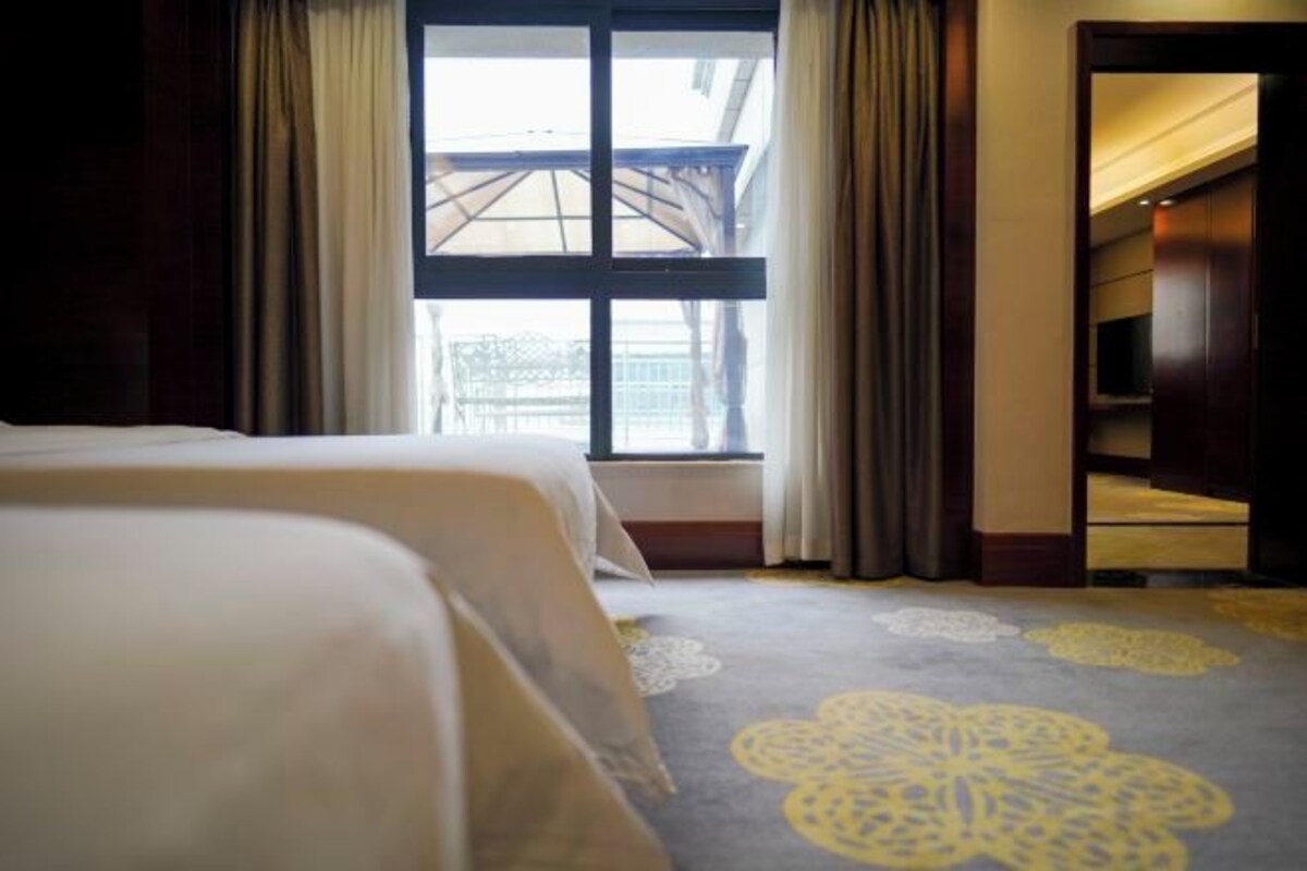 Camera d'albergo con un letto grande, una finestra con tende e vista sull'esterno.