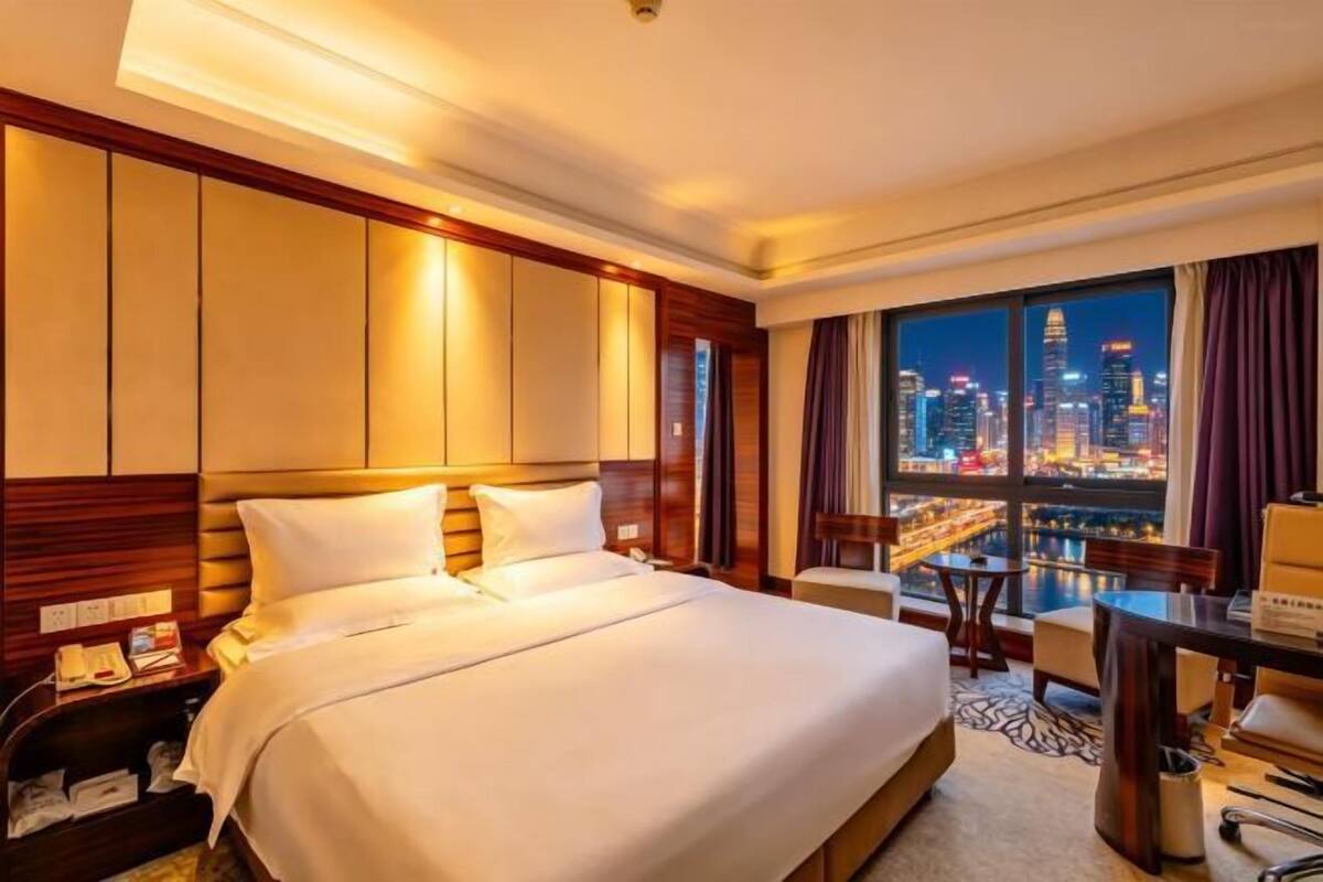 Une chambre d’hôtel avec un grand lit, un bureau et une vue sur le paysage urbain.