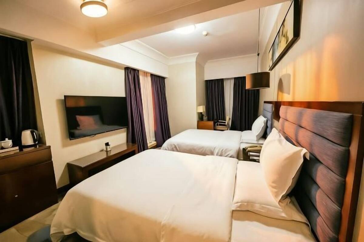 Une chambre d’hôtel avec deux lits, une télévision, un bureau et une table de chevet.